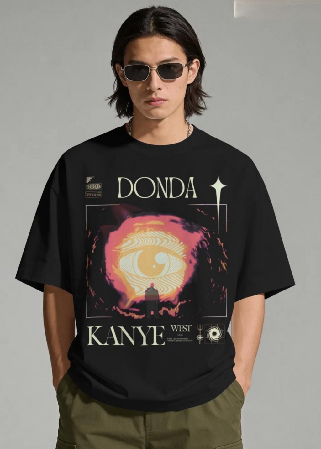 Person wearing a black t-shirt with 'Donda' and 'Kanye West' graphic design.