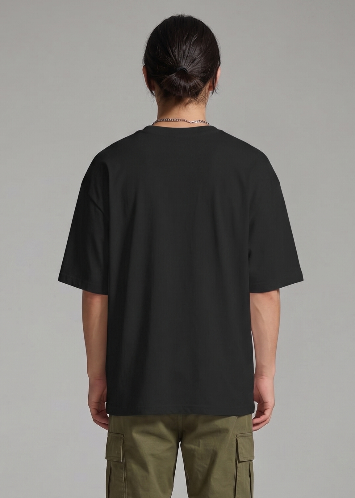 Person wearing a black oversized t-shirt and green cargo pants on a gray background